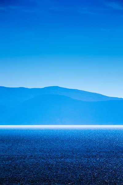 Mar azul y cielo con montañas lejanas en el fondo — Foto de Stock