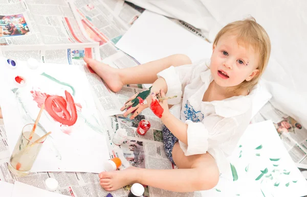 Veselé dítě kreslí obrázky na noviny — Stock fotografie
