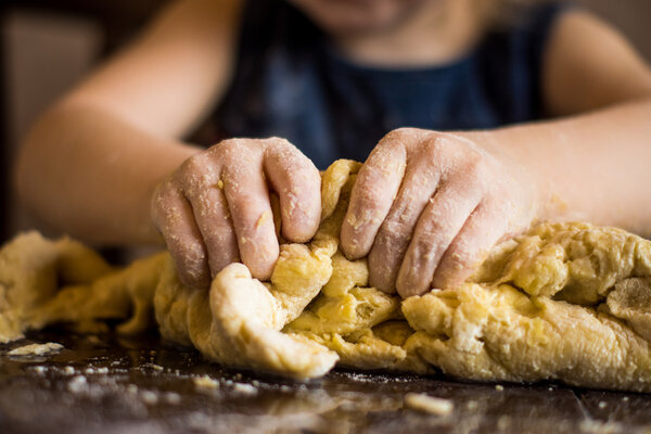 children's hands knead the dough