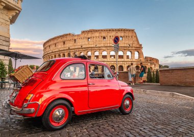 Roma, İtalya 17.07.2021: Küçük kırmızı Fiat 500 gün batımında kolezyumun önünde ve arkasında piknik sepeti ile