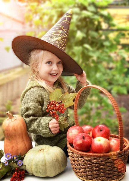 一个戴着黑色帽子的小女孩坐在水果和蔬菜中间 图库图片