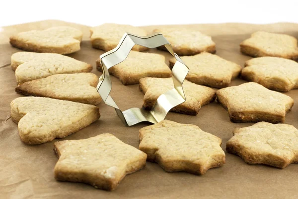 Biscuits de Noël et boîtes de cuisson sur un papier à pâtisserie — Photo