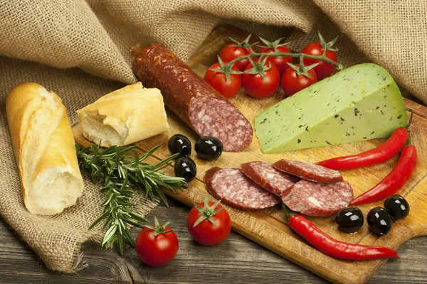 Salami and cheese platter with vegetable and herbs — Stock Photo, Image