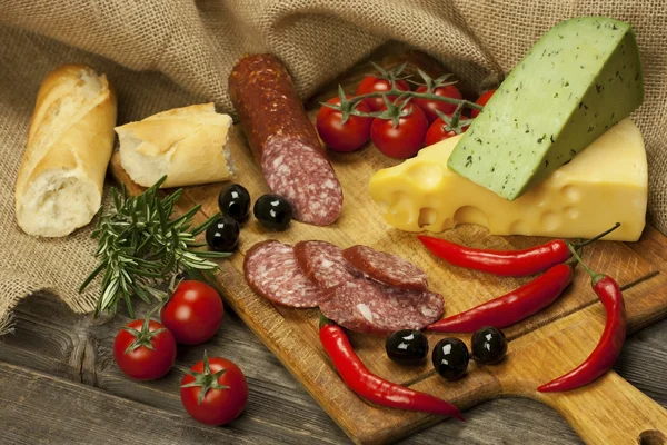 Salami and cheese platter with vegetable and herbs — Stock Photo, Image