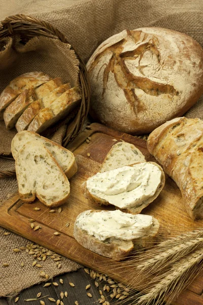 Čerstvý chléb a smetanový sýr na dřevěné desce — Stock fotografie