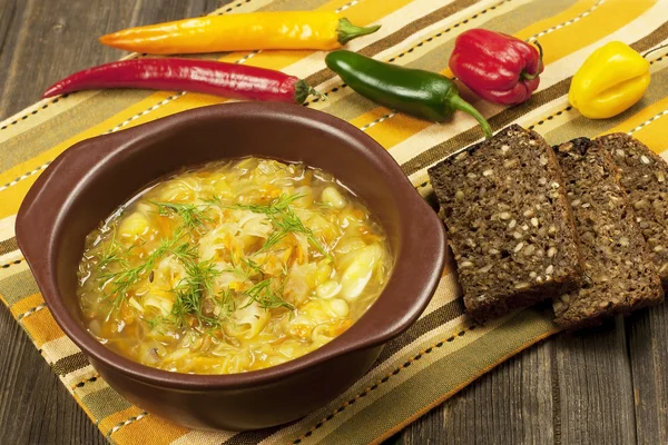 Zuurkool soep in keramische kom op houten tafel — Stockfoto