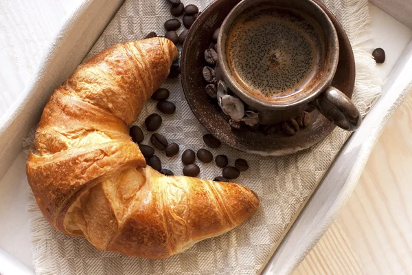 Croissant und Kaffee auf Holztisch — Stockfoto