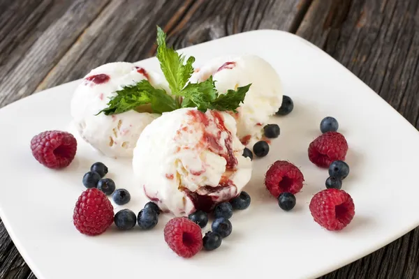 Balls of ice-cream garnished with berries on white plate — Stock Photo, Image