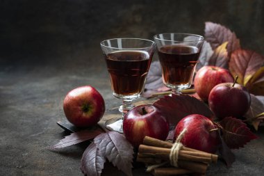 Elma şarabı ve tarçın çubukları ve koyu arkaplanda taze elmalar.
