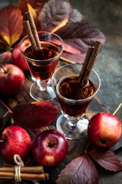 Elma şarabı ve tarçın çubukları ve koyu arkaplanda taze elmalar.