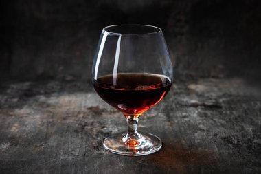 Alcohol  drink in large round glass - whisky, brandy, cognac on  dark background, selective focus with shallow depth of field