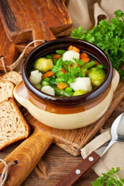 Rustik ahşap arka plan üzerinde havuç, karnabahar, maydanoz, bezelye ve yeşil fasulye ile Sebze çorbası 