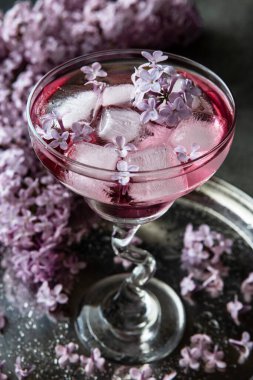 Leylak çiçekleriyle süslenmiş pembe alkol kokteyli, seçici odak, sığ alan derinliği