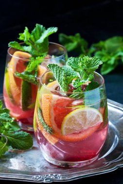 Koyu beton arka planda limon, portakal, greyfurt ve nane yapraklarıyla taze içecek, seçici odaklanma