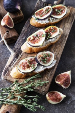 Breakfast with bruschettas with figs and cream cheese on wooden board, selective focus