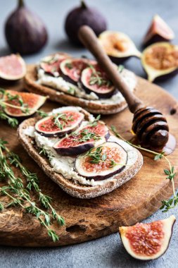 Breakfast with bruschettas with figs and cream cheese on wooden board, selective focus