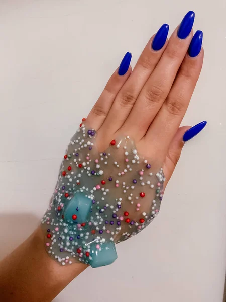 Hand met doorzichtig blauw glitter slijm — Stockfoto