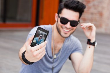 young male model making self portrait with a smartphone clipart