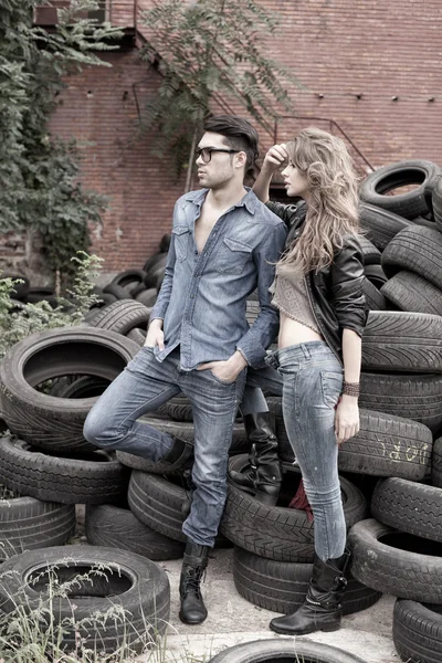 Pareja atractiva y de moda que usa jeans, dispara en una ubicación grumosa - orientación al paisaje con espacio para copiar —  Fotos de Stock