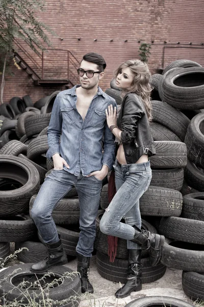 Sexiga och trendiga par klädd i jeans, skjuta i en grungy plats - liggande med kopia-utrymme — Stockfoto