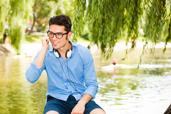 Handsome man standing on a bridge by the lake — Stock Photo, Image