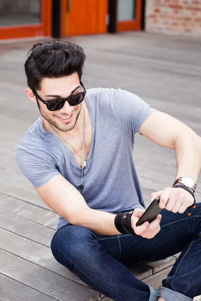 Attrayant jeune modèle masculin jouer à des jeux sur un téléphone intelligent — Photo