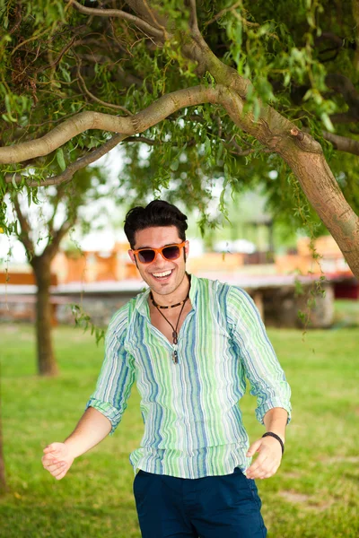 Homem bonito usando óculos de sol se divertindo no parque — Fotografia de Stock