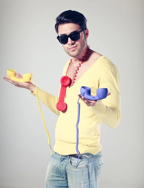 Handsomen und lustiger Typ mit Hipsterbrille und bunten Telefonen — Stockfoto