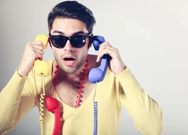 Tipo divertido centro de llamadas con gafas hipster y teléfonos de colores —  Fotos de Stock