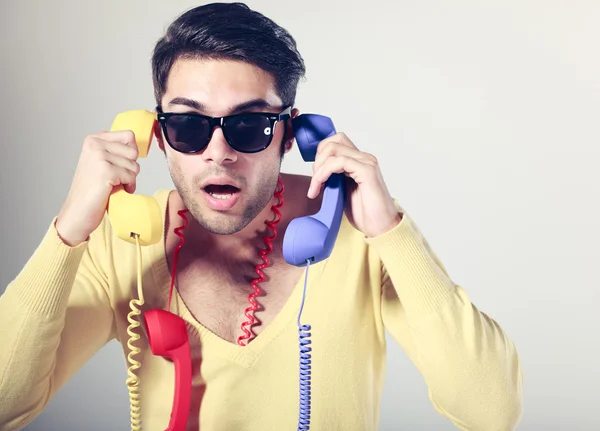 Grappige call center man met hipster bril en colouful telefoons — Stockfoto