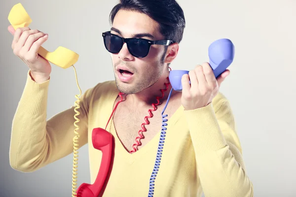 Lustiger Callcenter-Typ mit Hipster-Brille und bunten Telefonen — Stockfoto