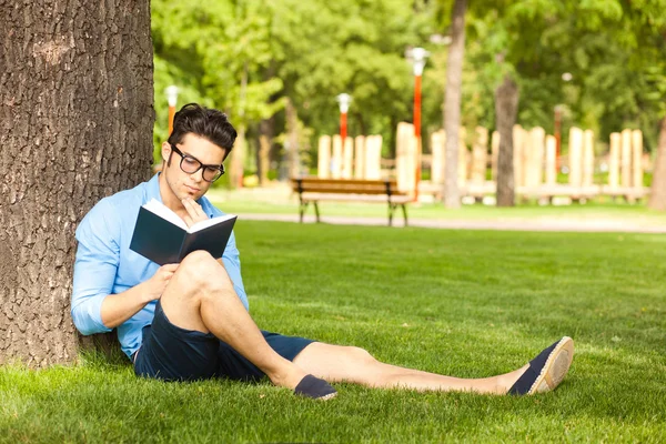 Człowiek posiadający książkę na trawie w parku — Zdjęcie stockowe
