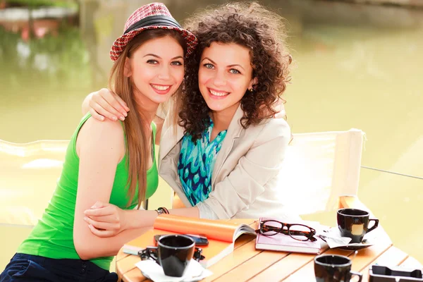 Twee mooie vrouwen drinken van koffie en glimlachen op de rivier sid — Stockfoto