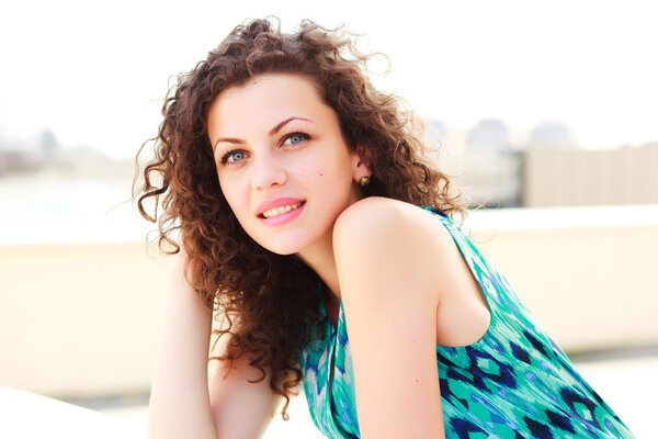 attractive women with curly hair posing outdoor on a sunny day