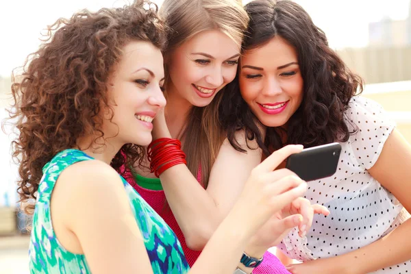 Three beautiful women looking on a smartphone Stock Picture
