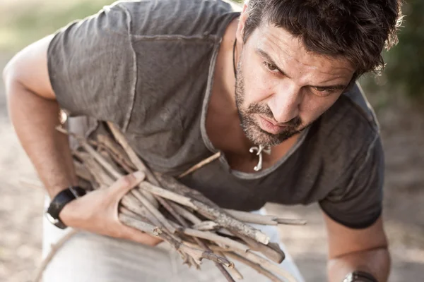 Rough man picking wood to make fire by the river - into the wild series — Stock Photo, Image