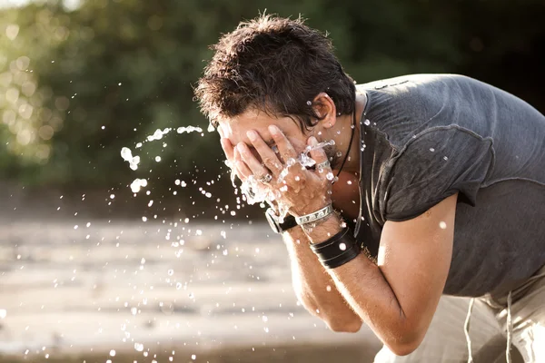 Mann wäscht sein Gesicht mit Wasser aus dem Fluss — Stockfoto