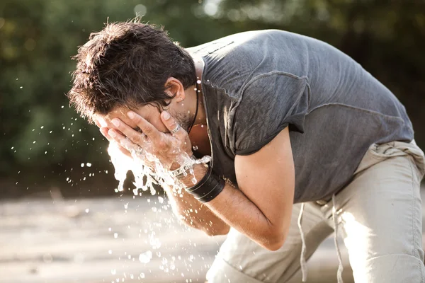 Mann wäscht sein Gesicht mit Wasser aus dem Fluss — Stockfoto