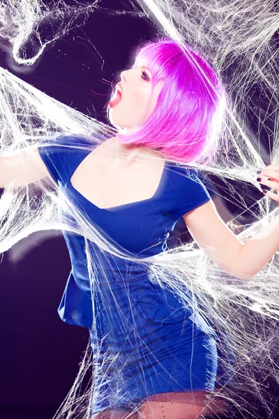 Mulher sexy com peruca roxa e intensa make-up preso em uma teia de aranha gritando moda atirar — Fotografia de Stock