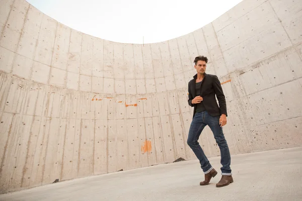 Homem atraente vestido de jeans e botas em um cenário grungy — Fotografia de Stock