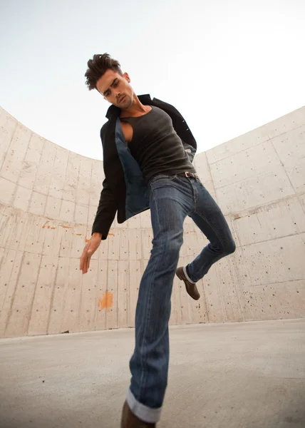 Homem atraente vestido de jeans e botas em um cenário grungy — Fotografia de Stock