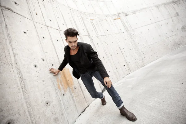 Homem atraente vestido de jeans e botas em um cenário grungy — Fotografia de Stock