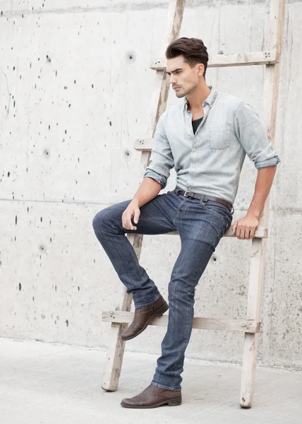 Attractive man dressed in jeans and boots in a grungy scenary — Stock Photo, Image