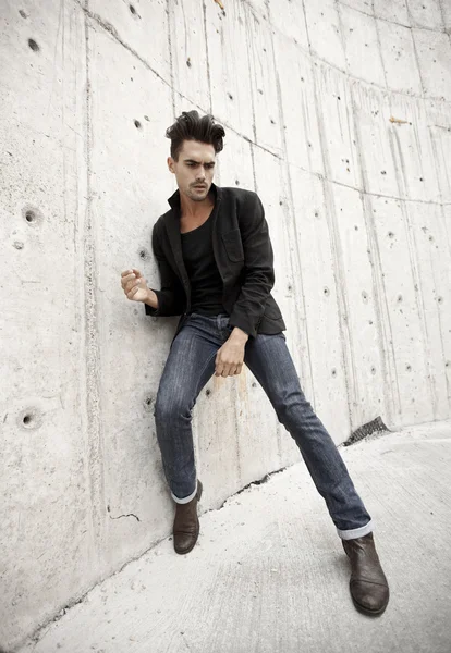 Attractive man dressed in jeans and boots in a grungy scenary Stock Picture