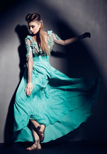 Beautiful woman in green dress posing dramatic indoors against grunge background — Φωτογραφία Αρχείου