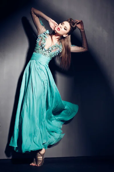 Beautiful woman in green dress posing dramatic indoors against grunge background — Φωτογραφία Αρχείου