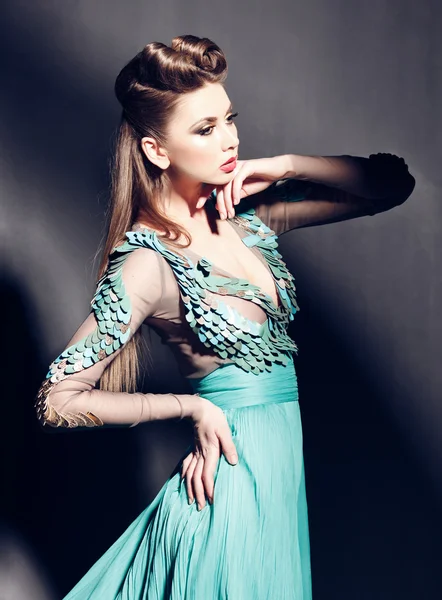 Beautiful woman portrait in green dress posing dramatic indoors against grunge background — Stock Photo, Image