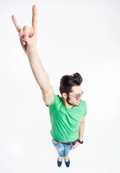 Gracioso hombre guapo con gafas hipster mostrando "nos rock" y sonriendo - tiro de gran angular — Foto de Stock