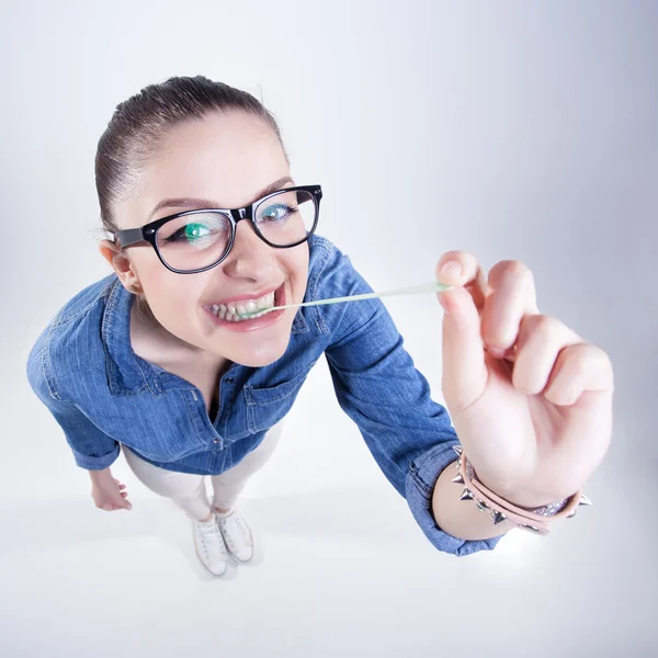 Pretty girl with perfect teeth wearing geek glasses smiling and playing with chuwing gum — Stock Photo, Image