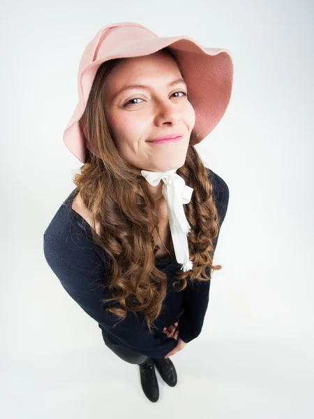 Мила дівчина зі смішним капелюхом посміхається в студії — стокове фото
